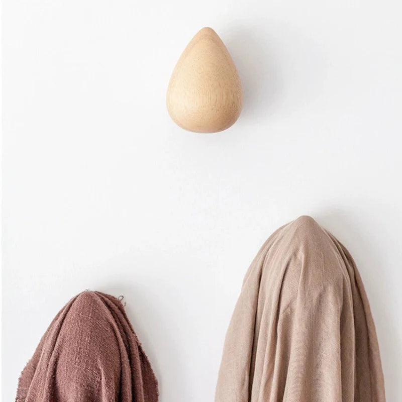 Wooden teardrop-shaped hook with fabric draped over it on a white wall