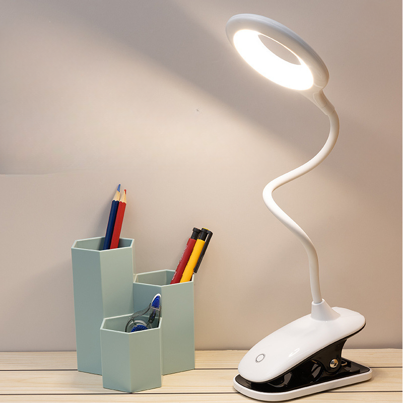 White LED desk lamp with flexible neck on a wooden surface next to a pen holder with stationery items.