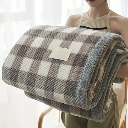 Person holding a checkered blanket with a visible brand label against a light background