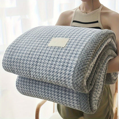 Person holding a folded gray blanket with a plain background