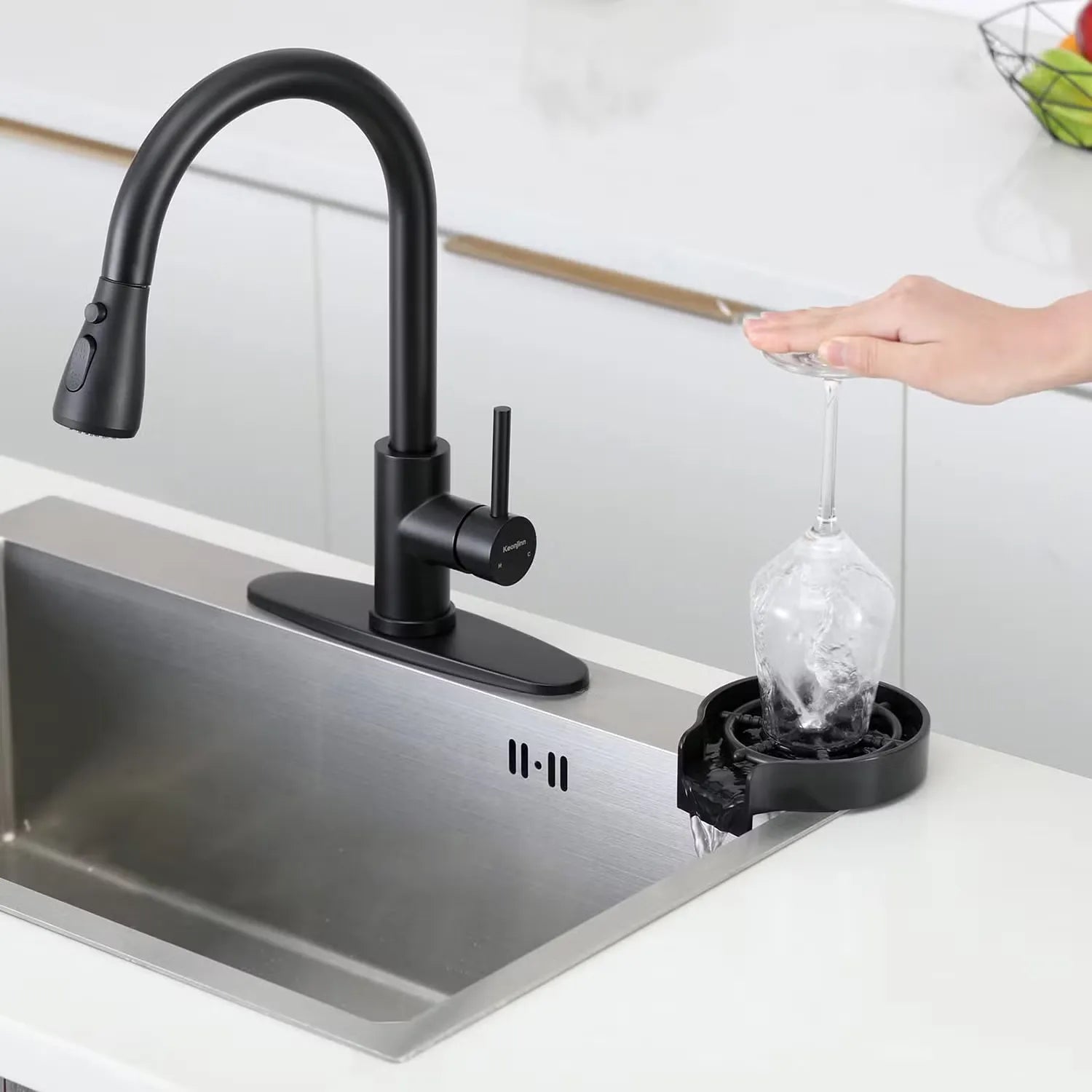 Black kitchen faucet with a sink and a hand holding a glass under running water.